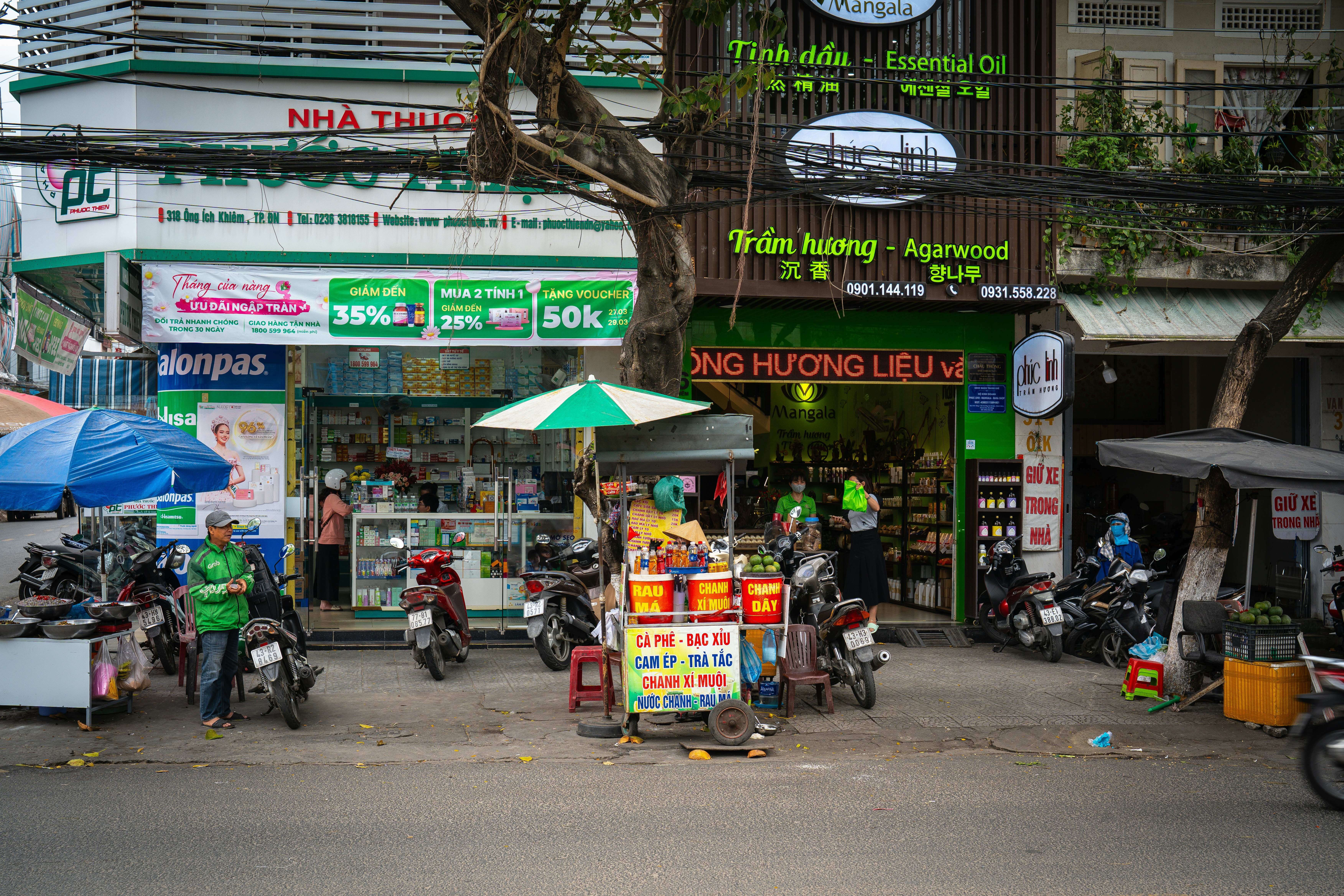 Street scene with shops, scooters, and people.